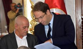 Youssef Chahed et Hassine Abassi en train de lire les clauses de l'accord conclu. 