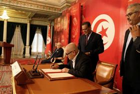Hassine Abassi en train de signer le document de Carthage. 